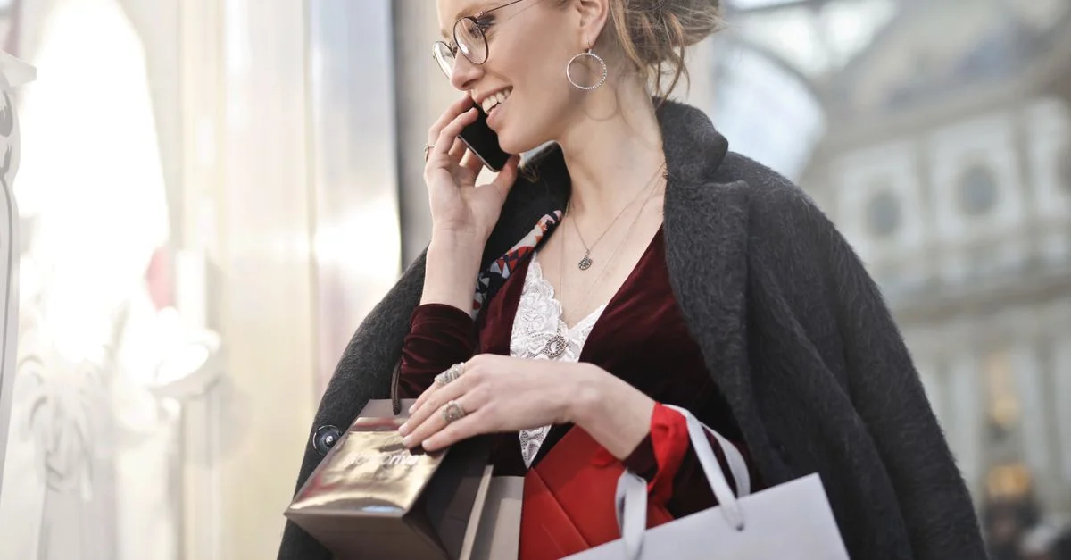 Femme élégamment habillée faisant du shopping avec des sacs et parlant au téléphone dans la Galleria Vittorio Emanuele II à Milan.
